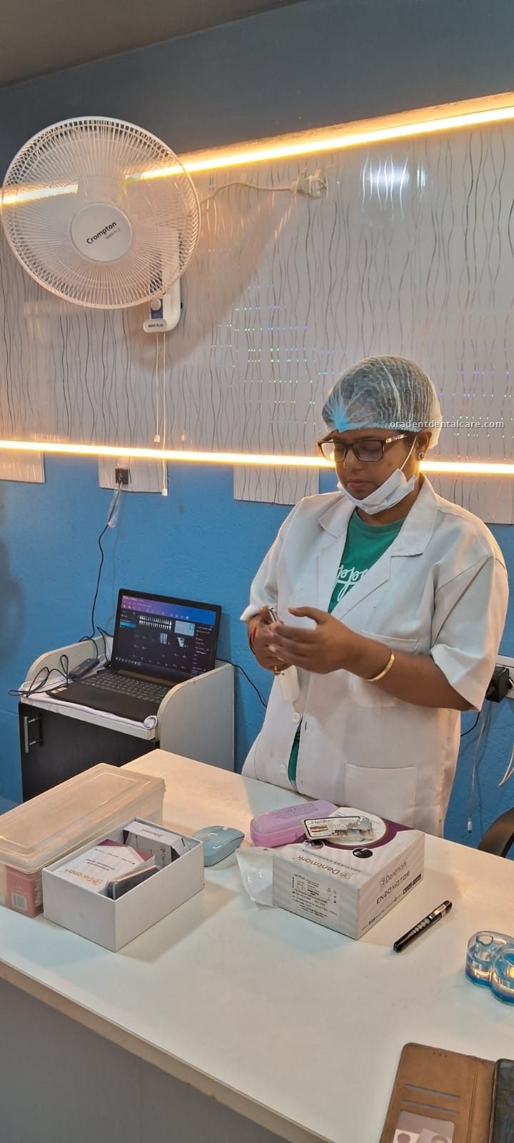 Dentist in cap and gown preparing instruments at the desk at ORADENT Dental Care