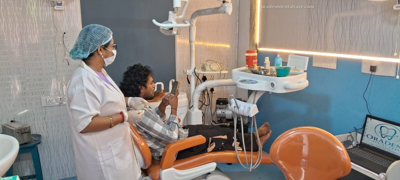 Dentist beside a patient seated in the dental chair at ORADENT Dental Care