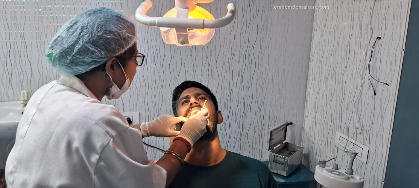Dentist treating a smiling patient in the dental chair at ORADENT Dental Care