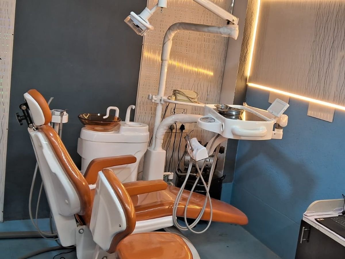 Dental chair and delivery unit seen from the patient side, with instrument tray and overhead light